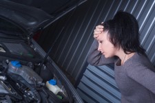 Worried Woman Looking at her Car Engine