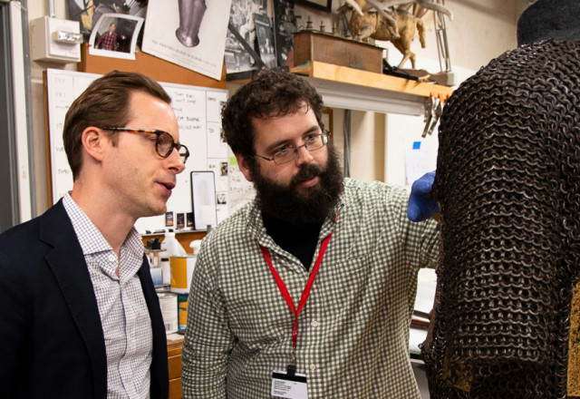 John Byck and a colleague inspect a suit of mail and plate armor.