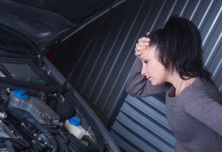 Worried Woman Looking at her Car Engine