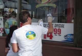 Volunteers removing graffiti from a  local storefront.