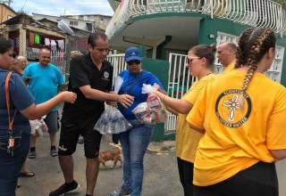 Volunteer Ministers help Jorge Navarro Suárez (in black) distribute supplies to his constituents.