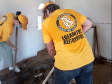  Volunteer Ministers do the arduous work of digging up dried mud that has hardened into a dense mass in a local home.